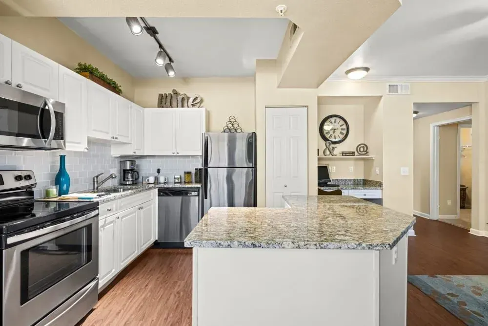 Kitchen with white cabinets, stainless steel appliances, and a granite island.