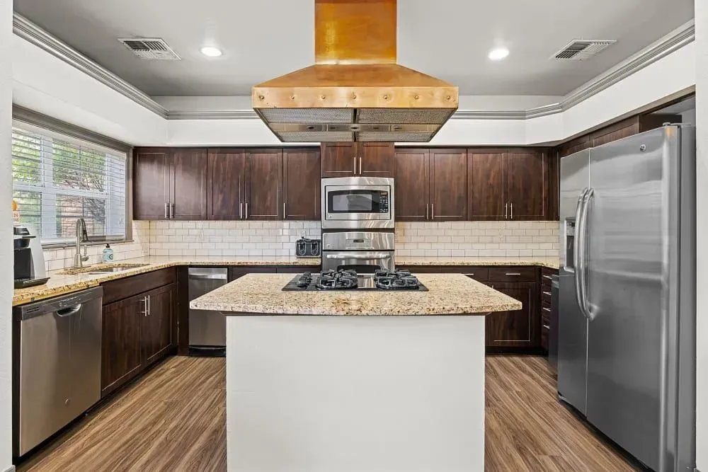 Spacious kitchen with dark wood cabinets, stainless steel appliances, and a center island with a granite countertop.