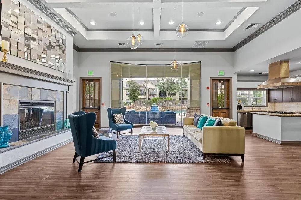 Spacious area with fireplace, seating, and a view of an outdoor pool area. Gold and teal color scheme.