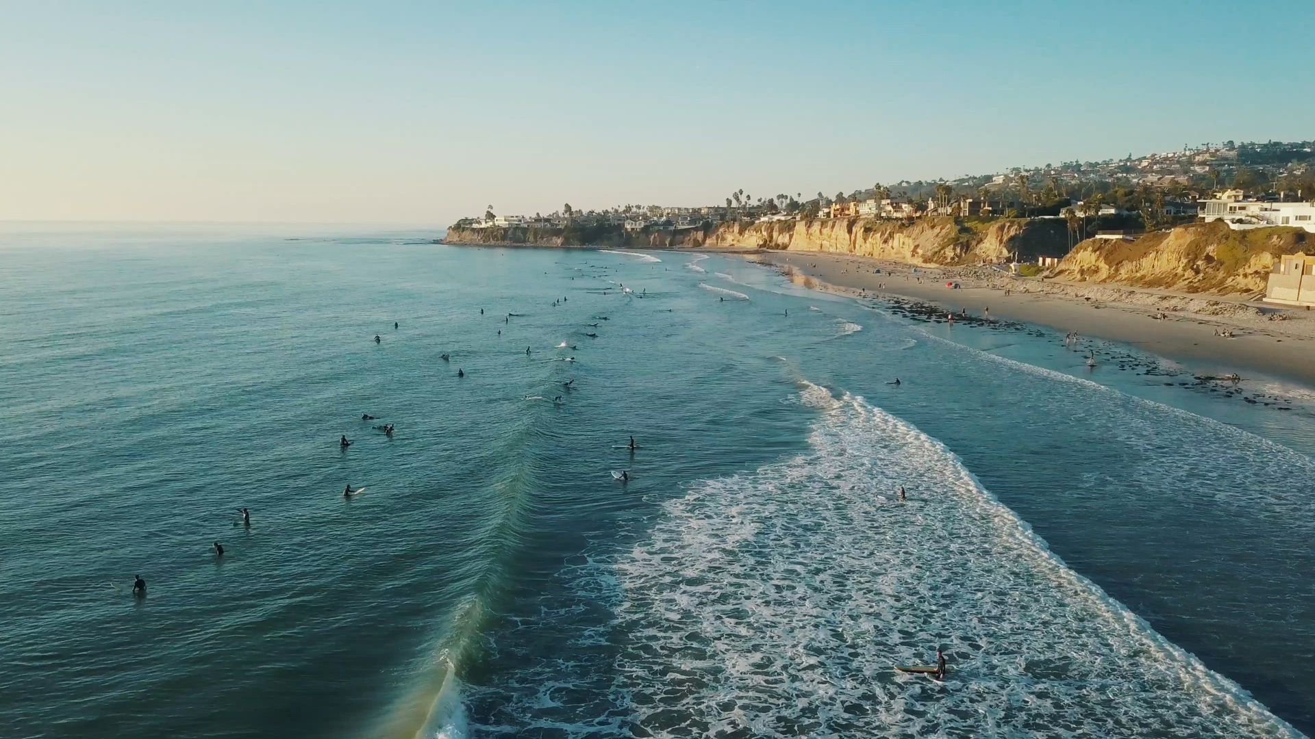 Wooden office with desk, green chairs, and bookcase. Laptop and statue on the desk.