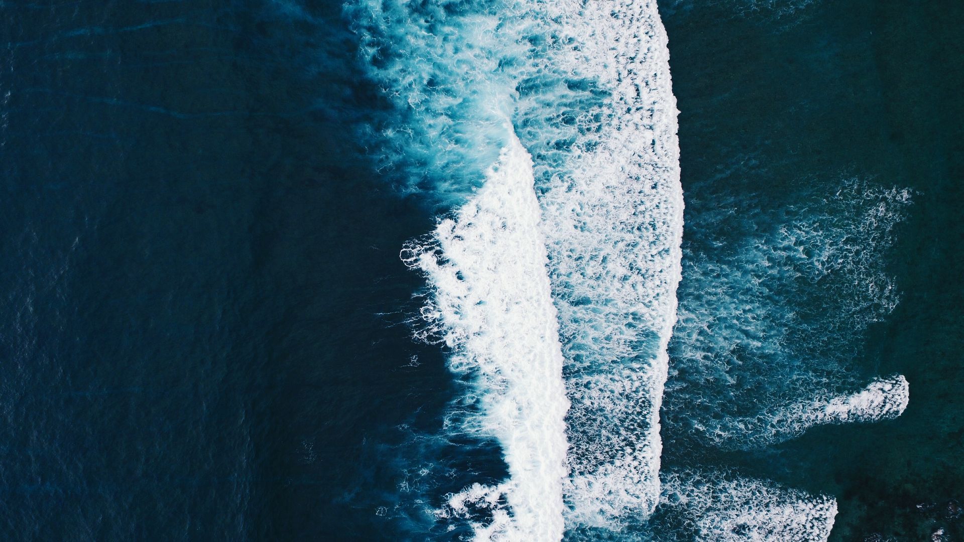 Wooden office with desk, green chairs, and bookcase. Laptop and statue on the desk.