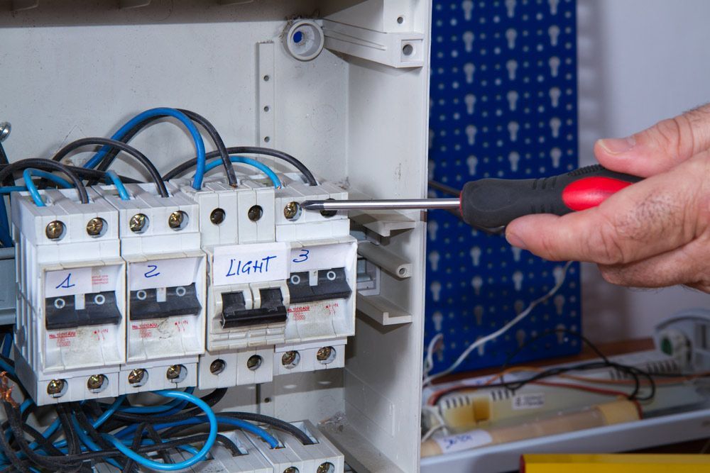 A Person is Using a Screwdriver to Fix an Electrical Box — Gealy's Air-Conditioning, Refrigeration & Electrical in Nambour, QLD