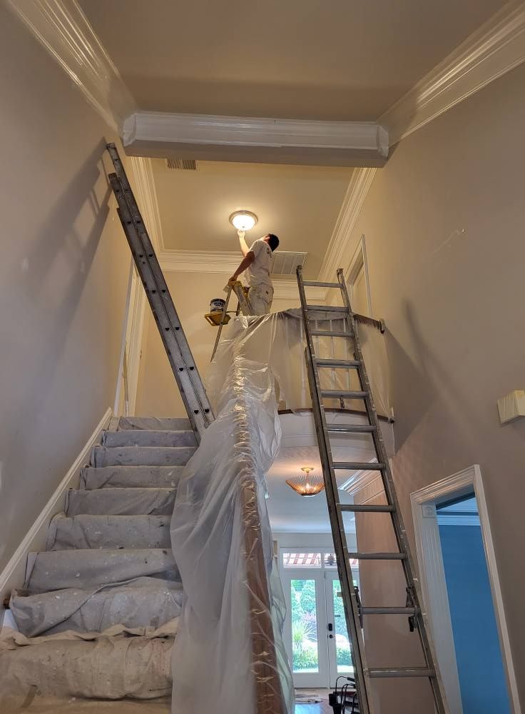 A man is standing on a ladder painting a wall.