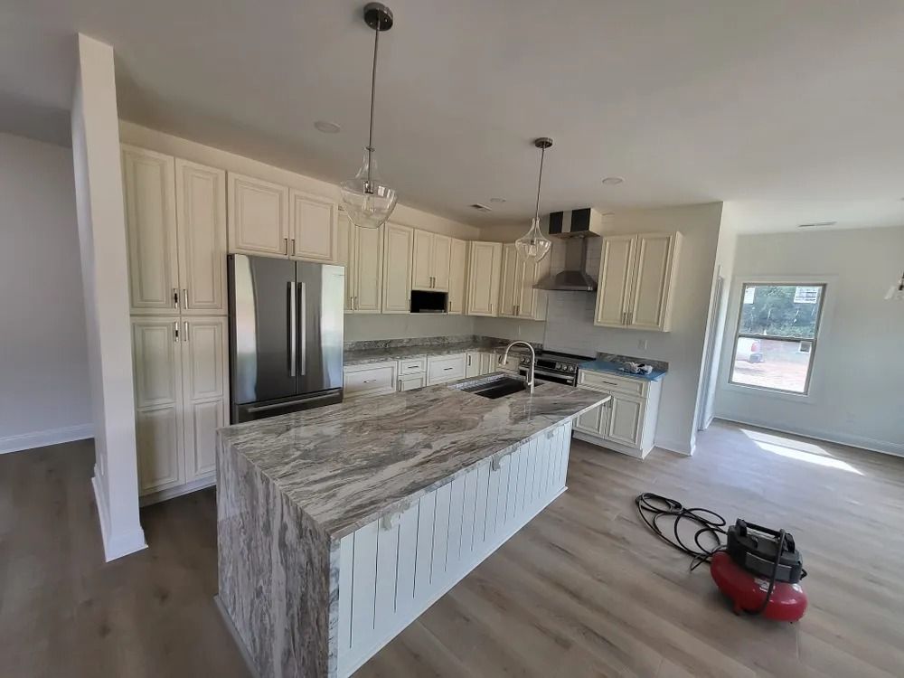 A kitchen with white cabinets , granite counter tops , stainless steel appliances and a vacuum cleaner.