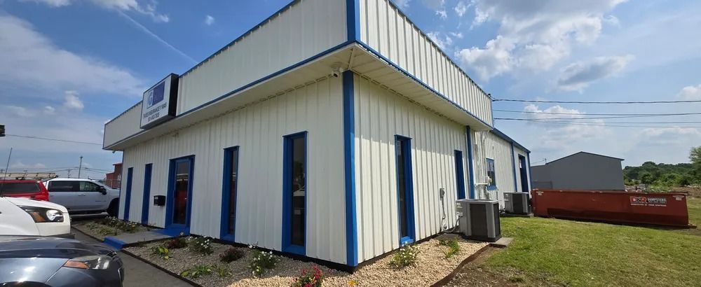 A white and blue building with a lot of windows and a car parked in front of it.