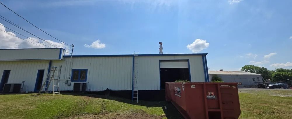 A large white building with a red dumpster in front of it.