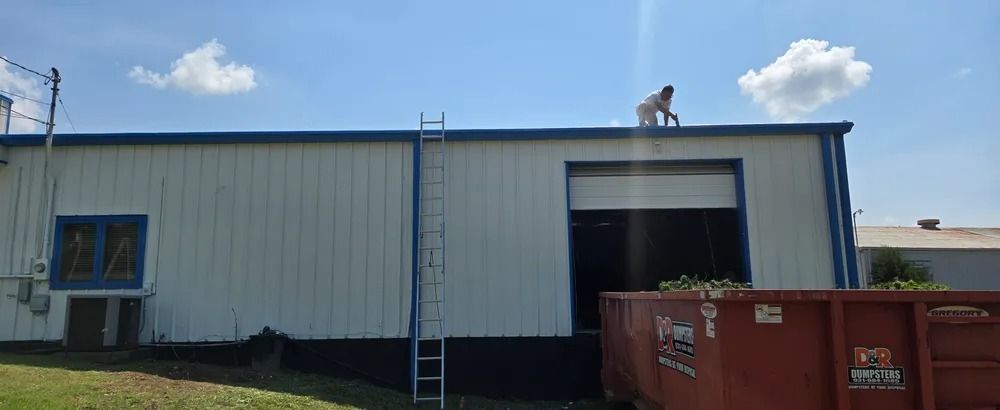 A man is standing on top of a building with a ladder.