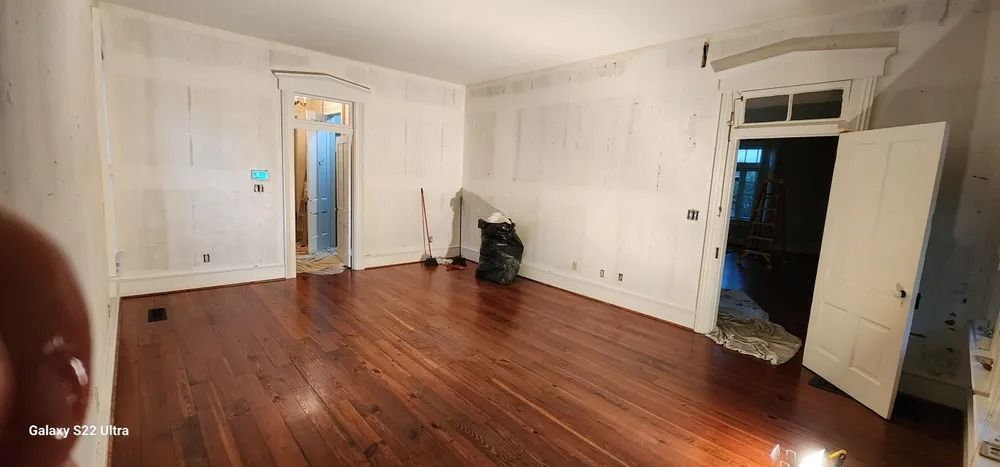 An empty living room with hardwood floors and white walls.