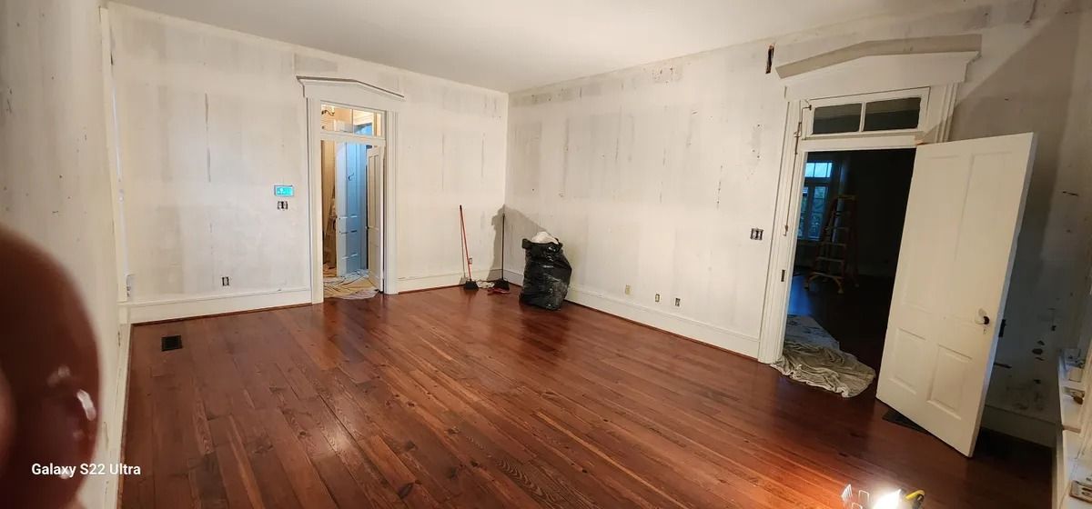An empty living room with hardwood floors and white walls.