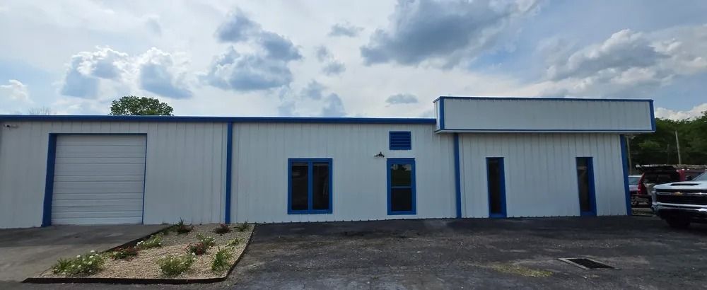 A white and blue building with a truck parked in front of it.