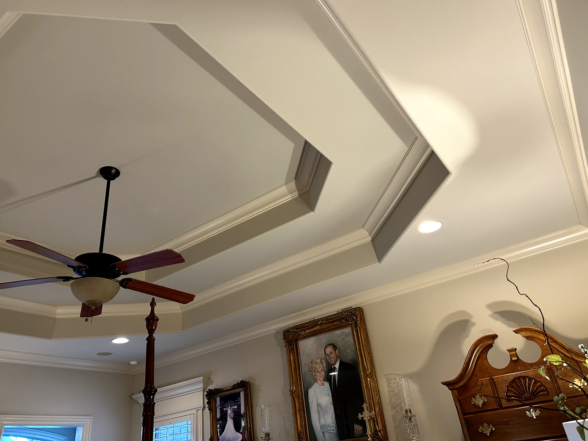A bedroom with a ceiling fan and a picture on the wall