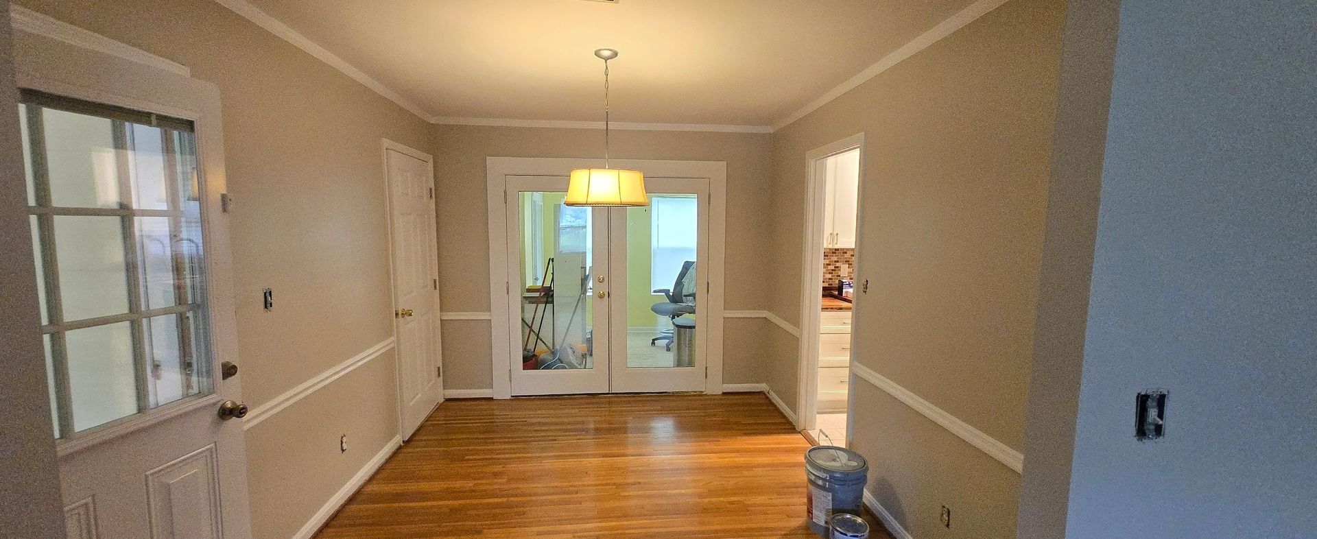 An empty dining room with hardwood floors and sliding glass doors.