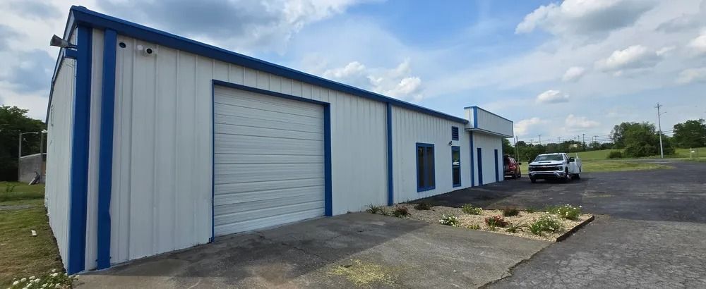 A white and blue building with a truck parked in front of it.