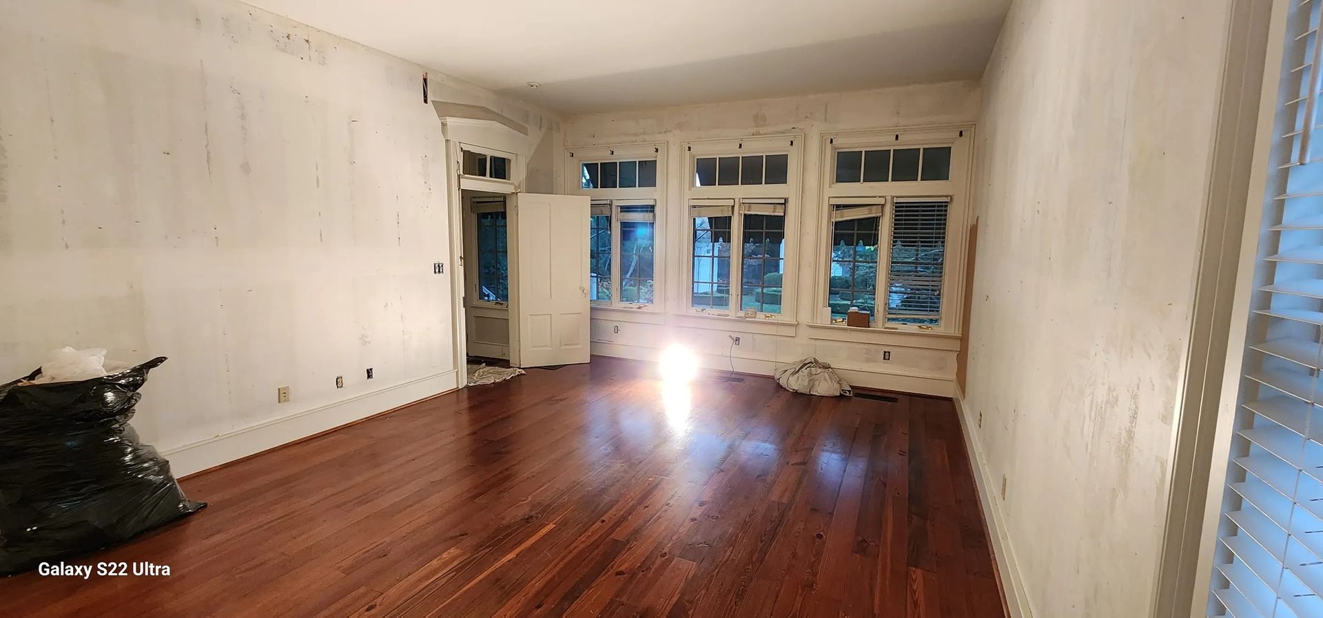 An empty room with hardwood floors and white walls.