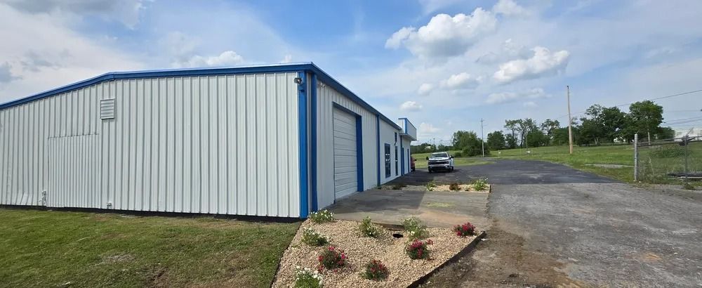 A white and blue metal building with a car parked in front of it.
