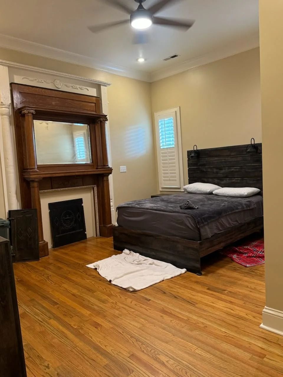 A bedroom with a bed , fireplace , mirror and ceiling fan.
