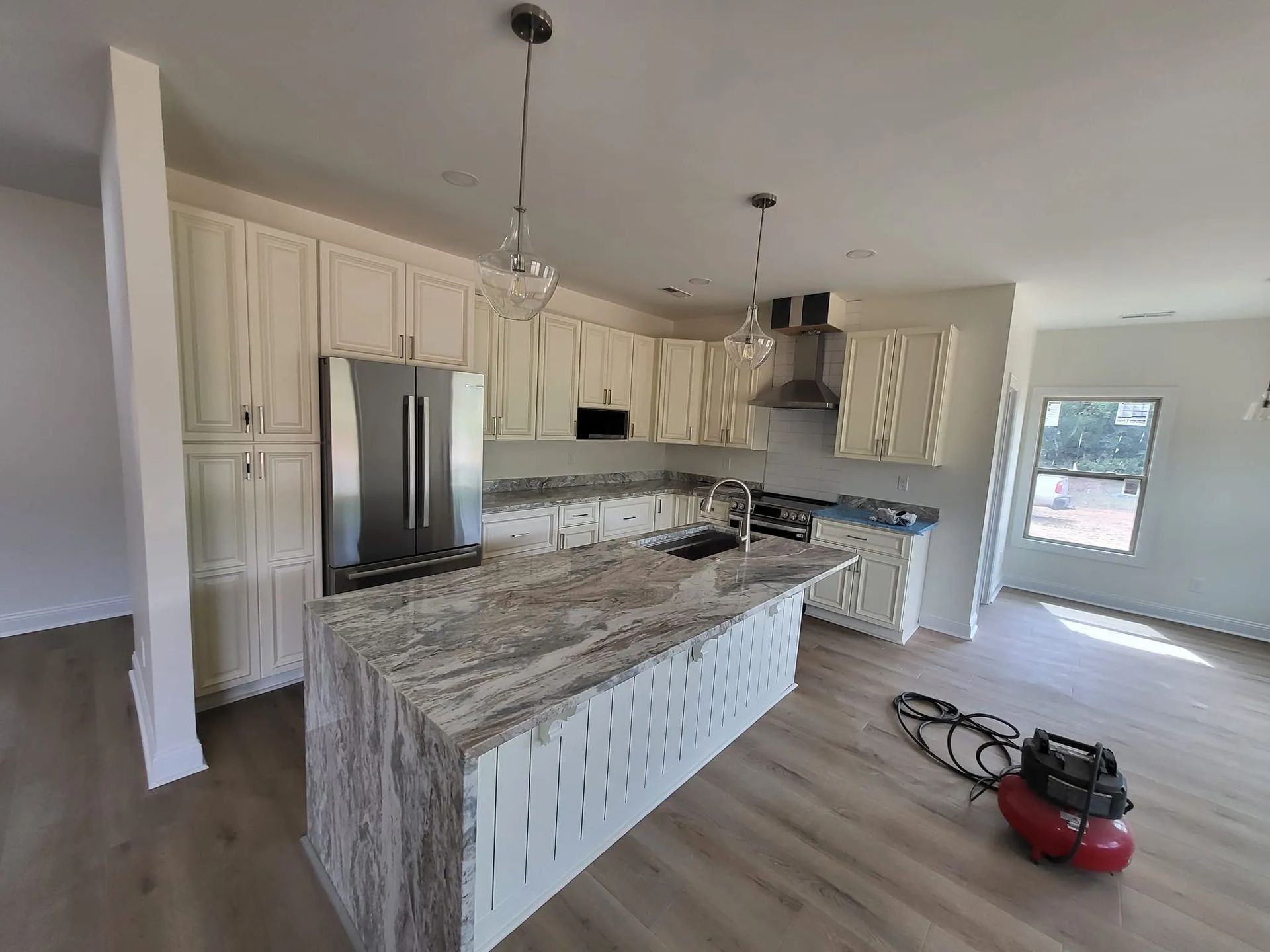 A kitchen with white cabinets , granite counter tops , stainless steel appliances , and a large island.