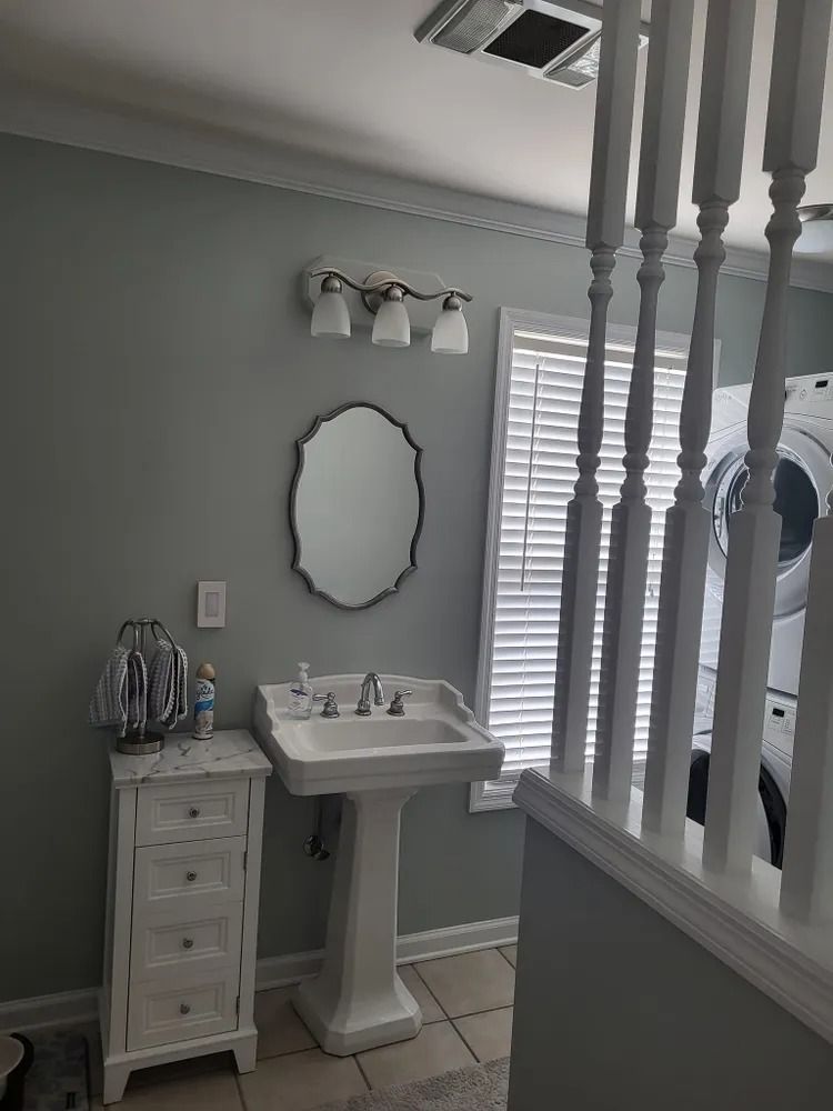 A bathroom with a sink , mirror , dresser and stairs.