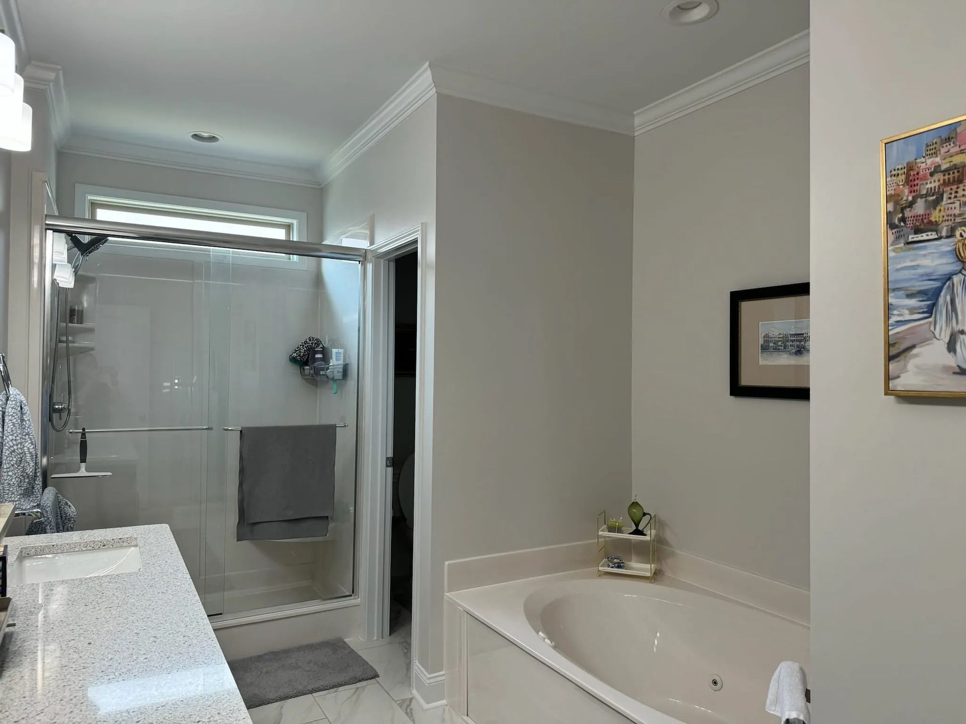 A bathroom with a tub , sink , shower and painting on the wall.