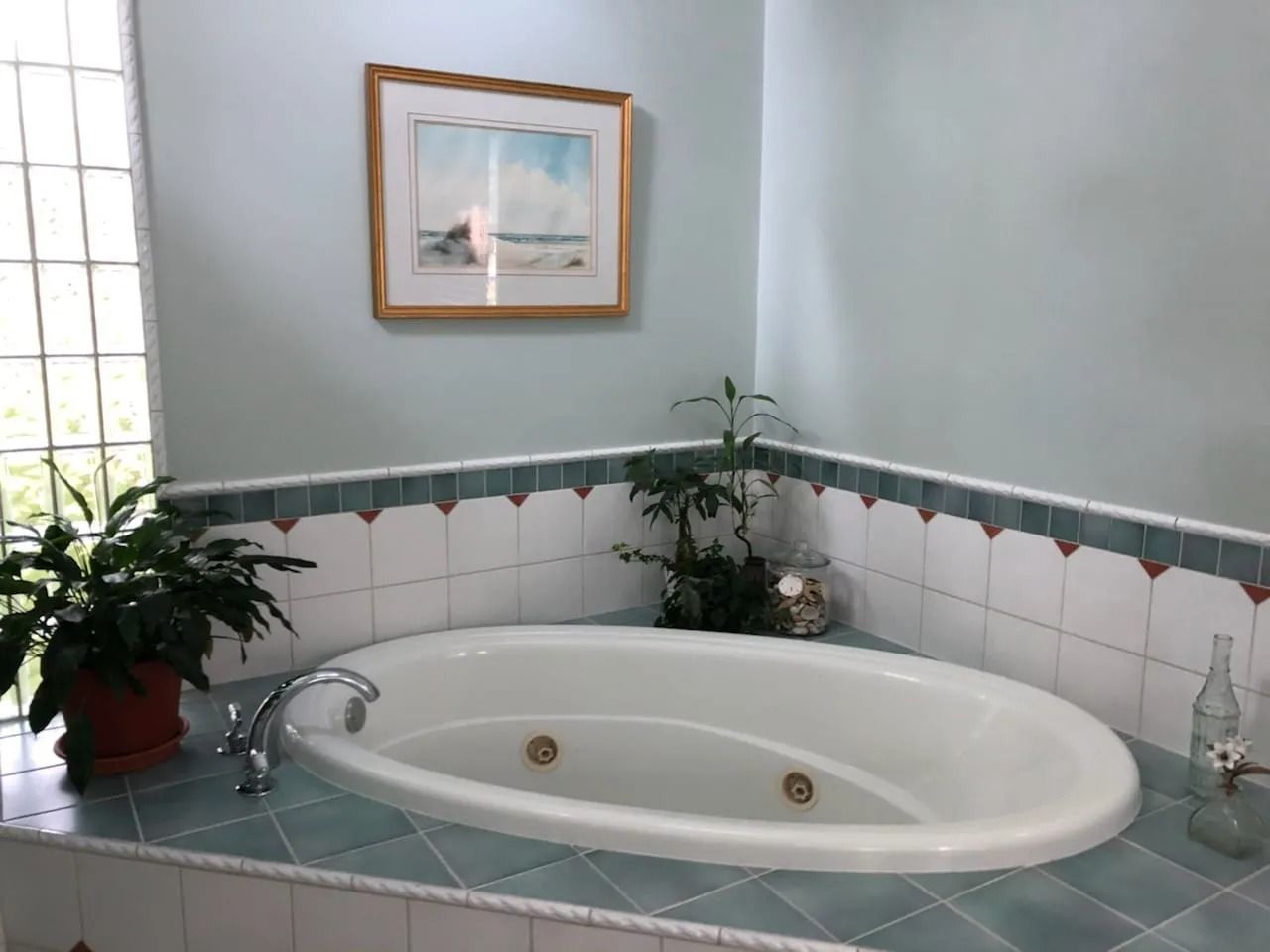 A bathtub in a bathroom with a picture on the wall above it