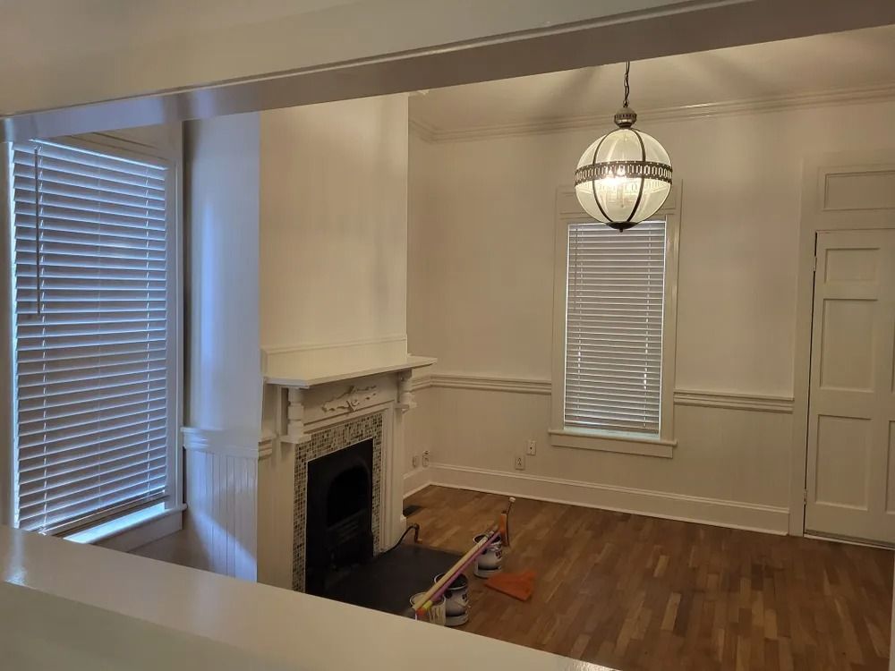 An empty living room with a fireplace and blinds.