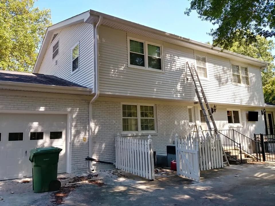 A white house with a green trash can in front of it
