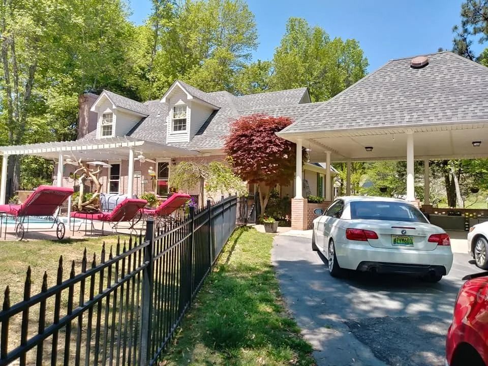 A white car is parked in front of a large house.