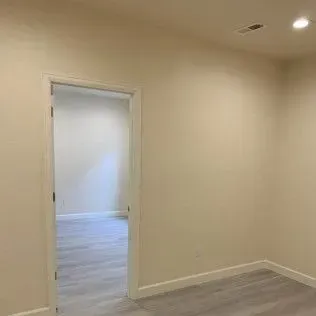 Open doorway leading into a room with light-colored walls and flooring.