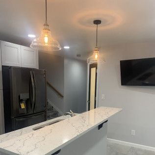 Kitchen with a white countertop, pendant lights, and stainless steel refrigerator.