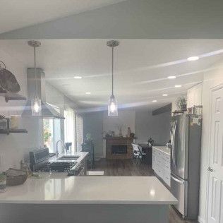 Kitchen with a white countertop island and stainless steel appliances. View to living area with fireplace.