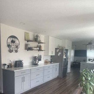 Kitchen with gray and white cabinets, stainless steel refrigerator, and dark wood floors.