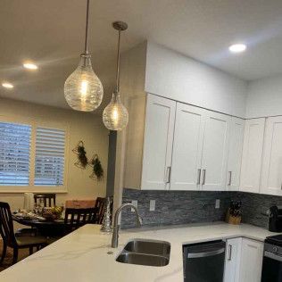 Kitchen with white cabinets, marble countertop, pendant lights, and stainless steel sink.