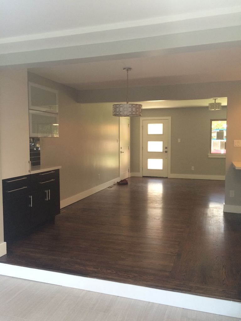 Interior of a home with dark wood floors, light walls, and a view through to the front door.
