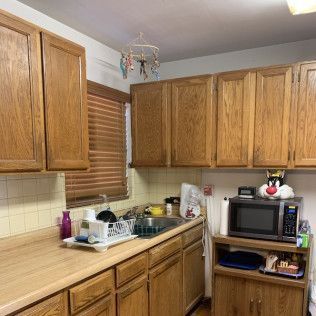 Kitchen with wooden cabinets, countertop, sink, and microwave. A mobile hangs from the ceiling.