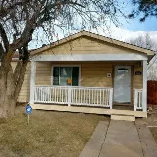 Interior view of a finished basement: door, staircase with black railings, gray walls, and carpet.
