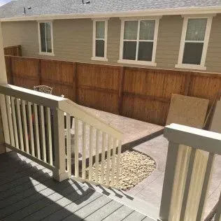 Backyard patio with wooden fence, deck, and rock bed.