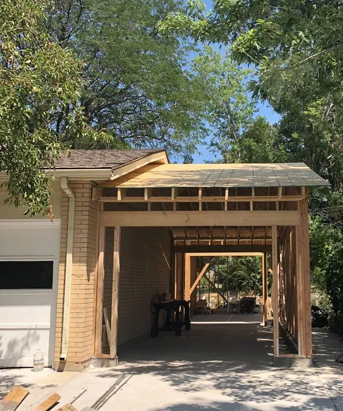 Construction of a wooden carport attached to a brick building.