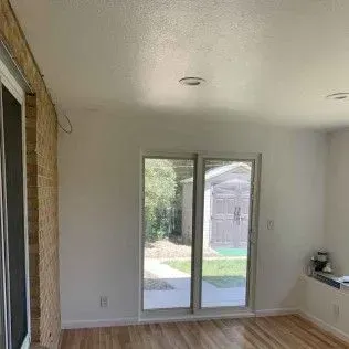 Room interior with sliding glass doors, brick wall, and hardwood floor.