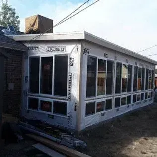 Sunroom addition under construction, with windows and protective wrapping.