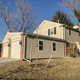 Beige and brick two-story house with attached garage, sunny day.