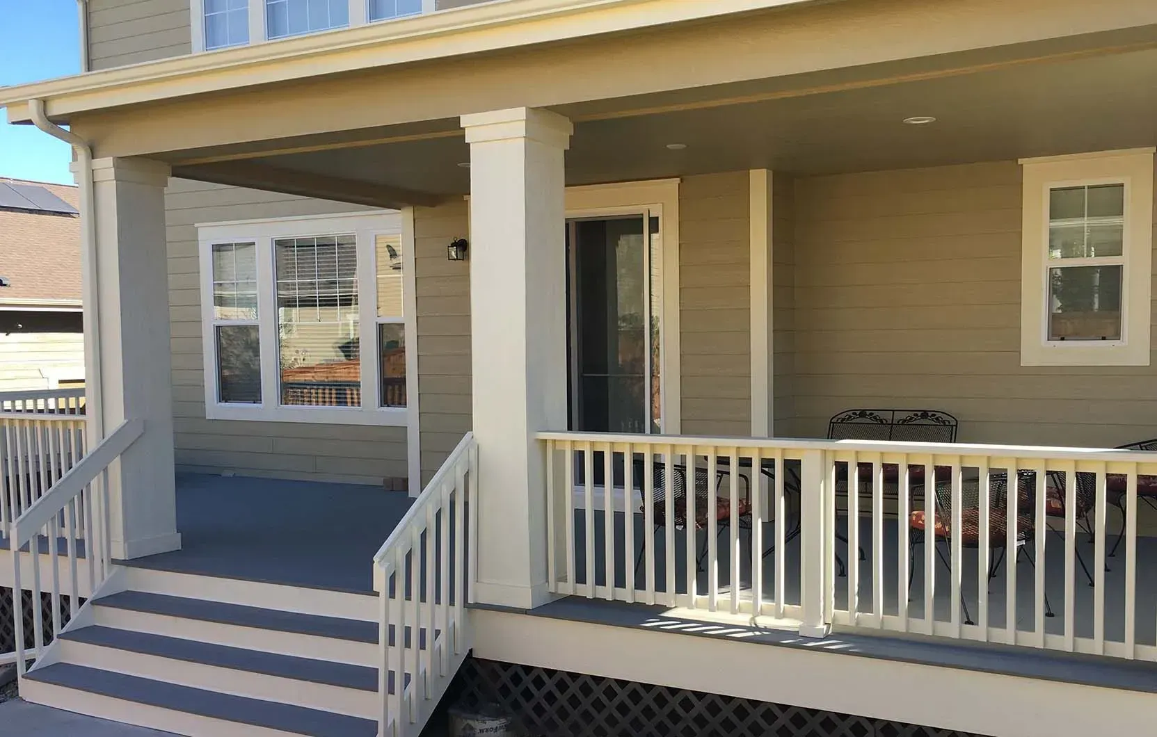 Beige porch with white railings, a gray deck, and a sliding glass door. A bay window is visible.