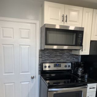 Kitchen with white cabinets, stainless steel appliances, and a tiled backsplash.