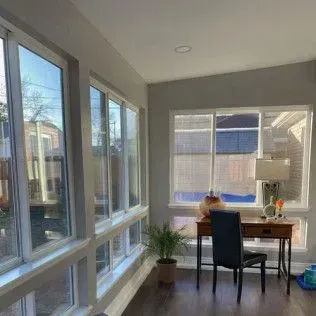 Sunroom with large windows and a desk. Sunlight floods the room.