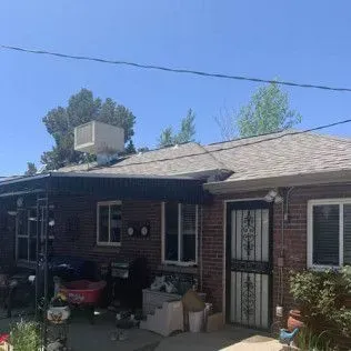 Brick building with black doors, windows, and gray roof under a clear, blue sky.