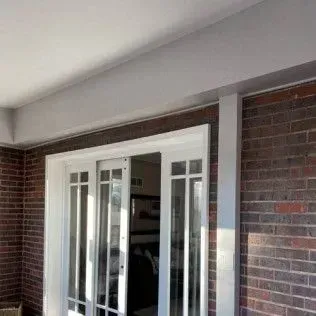 Brick exterior with white-framed glass doors under a white covered porch.