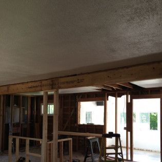 Interior of a room under renovation; exposed wooden framing, visible support beams, and unfinished ceiling.