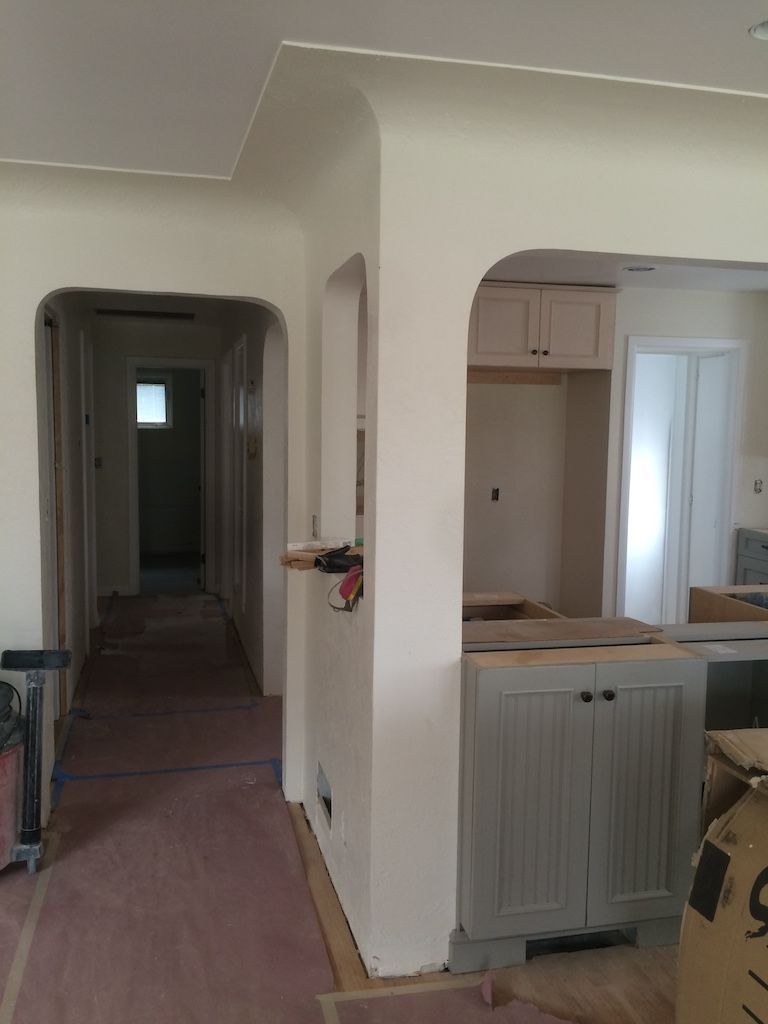Interior of a house under renovation with doorways and cabinets. Walls are painted light beige.