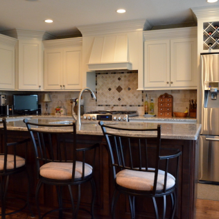 Kitchen with cream cabinets, dark wood island, stainless steel appliances, and bar stools.