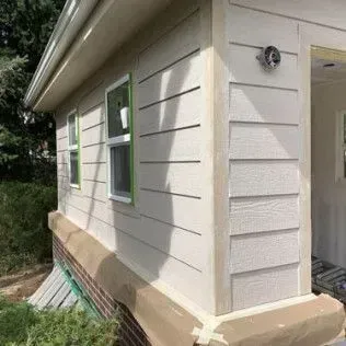 Exterior of a building with white siding, two windows, and security camera.