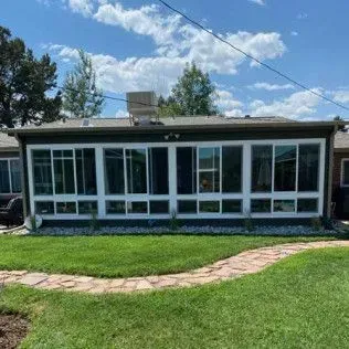 Sunroom with many windows, on a grassy lawn with a stone path.